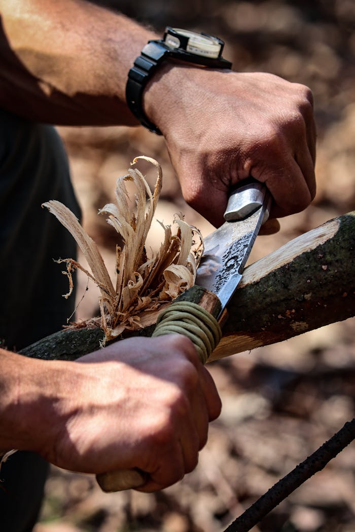 Home Close-up of hands skillfully carving wood with a knife, showcasing craftsmanship outdoors.